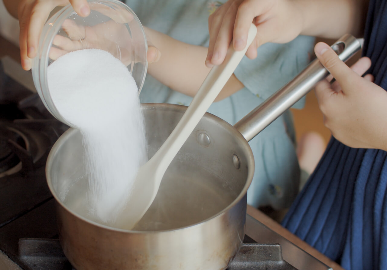 写真：溶けた寒天が入っている鍋に砂糖を投入する様子