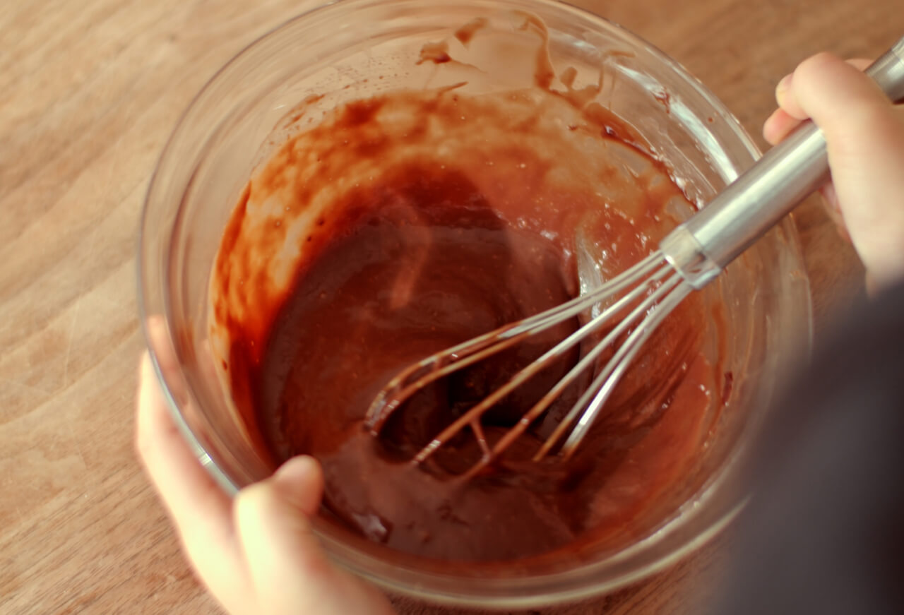 チョコレートが溶けたら湯せんから外し、卵を加えて泡立て器でなめらかになるまで混ぜる。