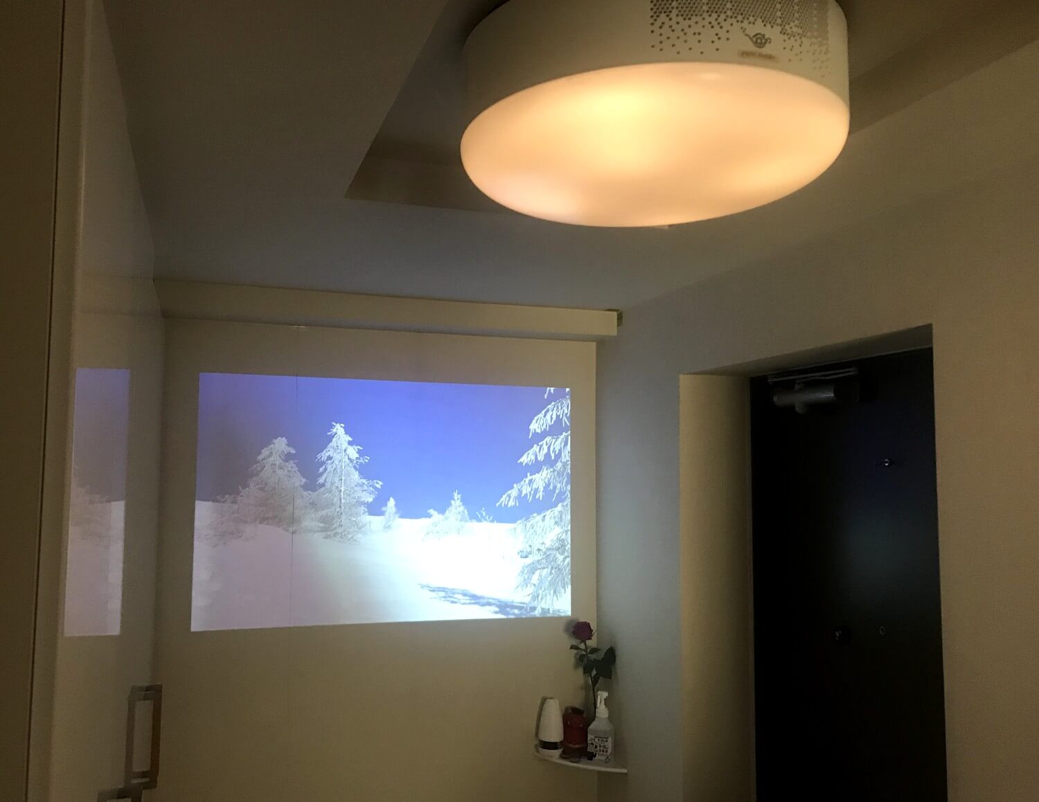 2018年に発売の初代モデルpopInAladdinは玄関の明かりとして設置。白い壁に「窓」を作る感覚で風景のコンテンツを投影するのがお気に入り