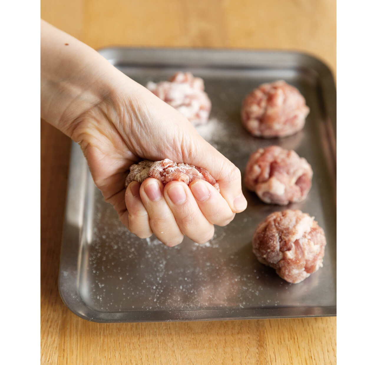 6等分にした豚肉をギュッと握ってボール状に。肉がはがれてくるようなら、表面にも粉をまぶし、形を整えればOK。