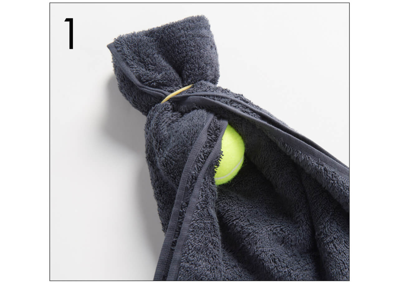 1.タオルの端を輪ゴムで留め、中にテニスボールを1個入れて包み、また輪ゴムで留める。