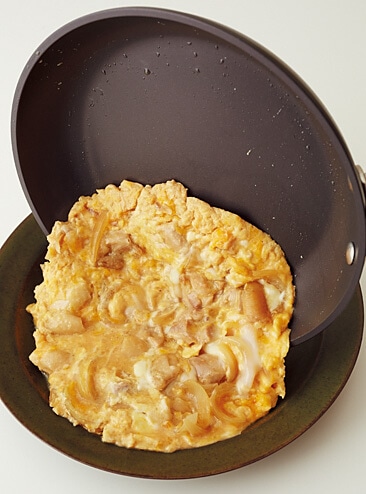 卵とじをフライパンからお皿にすべらせるように移す写真：フライパンで「鶏肉と玉ねぎの卵とじ」レシピ／小林まさみさん