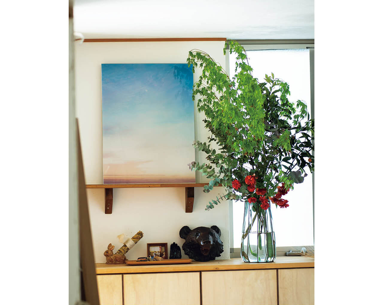 玄関には、モロカイ島で砂原さんが撮った初期の作品のそばに花とグリーンを。前の家から持ってきた紅葉や金柑の枝と花店で買ったお花を大森さんがアレンジ。