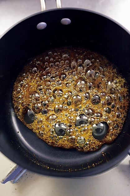 小さめのフライパンでキビ砂糖と水を入れ中火にかけ、揺すりながら砂糖を溶かしカラメルを作る写真