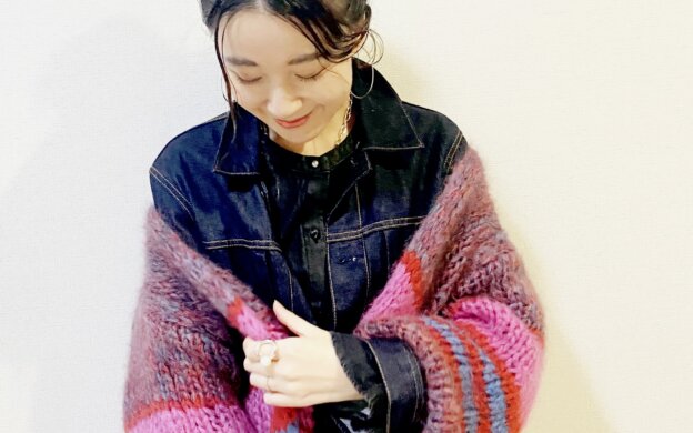 デニムジャケットとニットを着る女性
