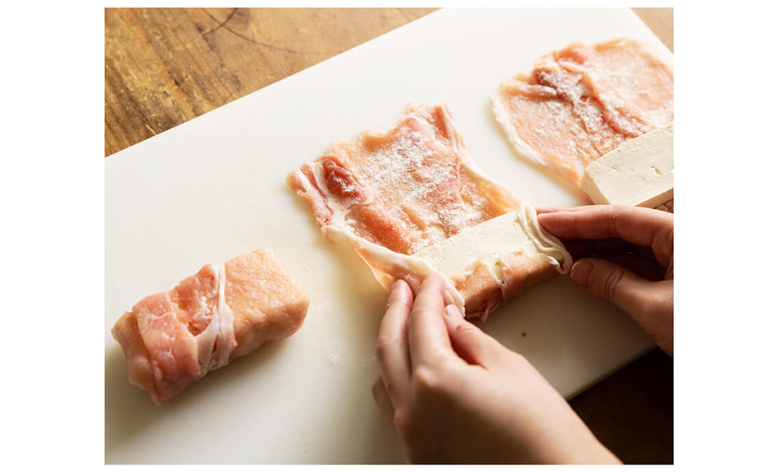 肉3枚で豆腐1切れを包む。左右の端も内側に折りたたみながら、くるくると巻いて包む。最後に握って、しっかり肉を豆腐にくっつける