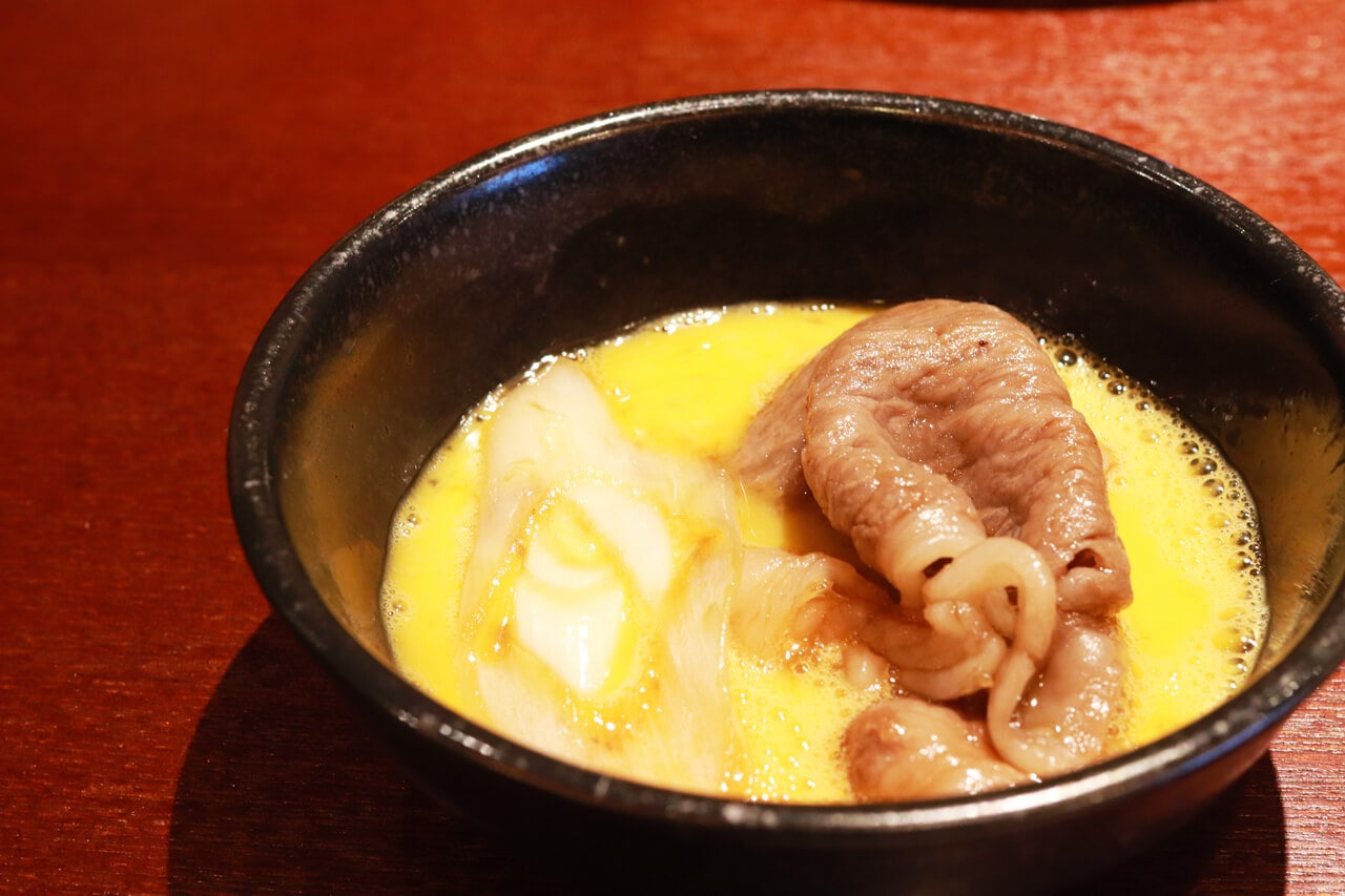 写真：浅草すき焼き店「ちんや」のすき焼き。たっぷり卵にねぎとすき焼き肉が盛られた様子