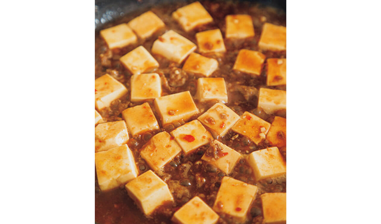 豆腐はコトコト煮て、味を中まで入れる。じっくり煮ると豆腐が締まって、茶色くなってくる