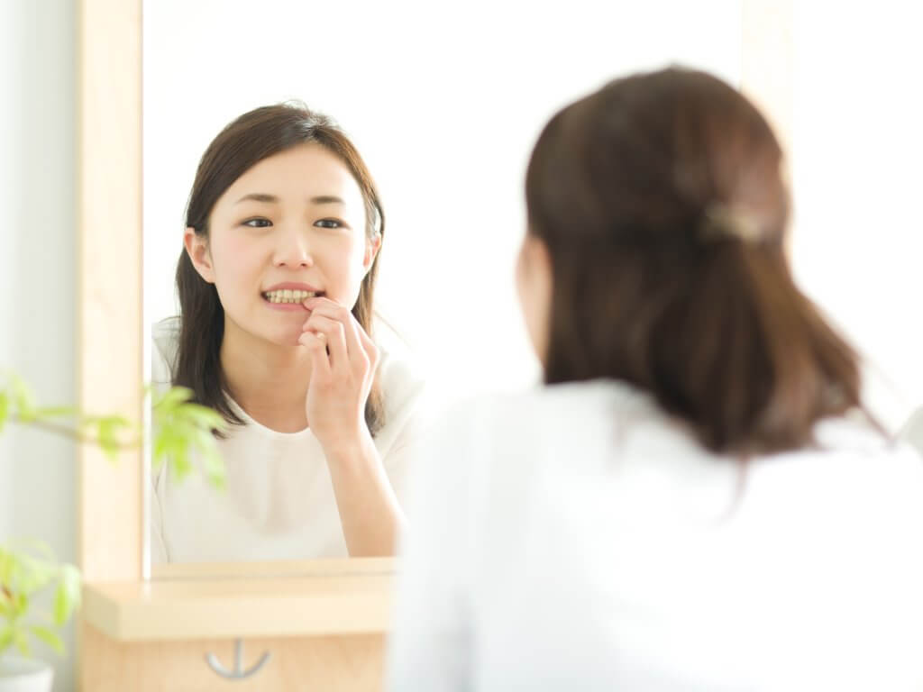 鏡で歯を見る女性