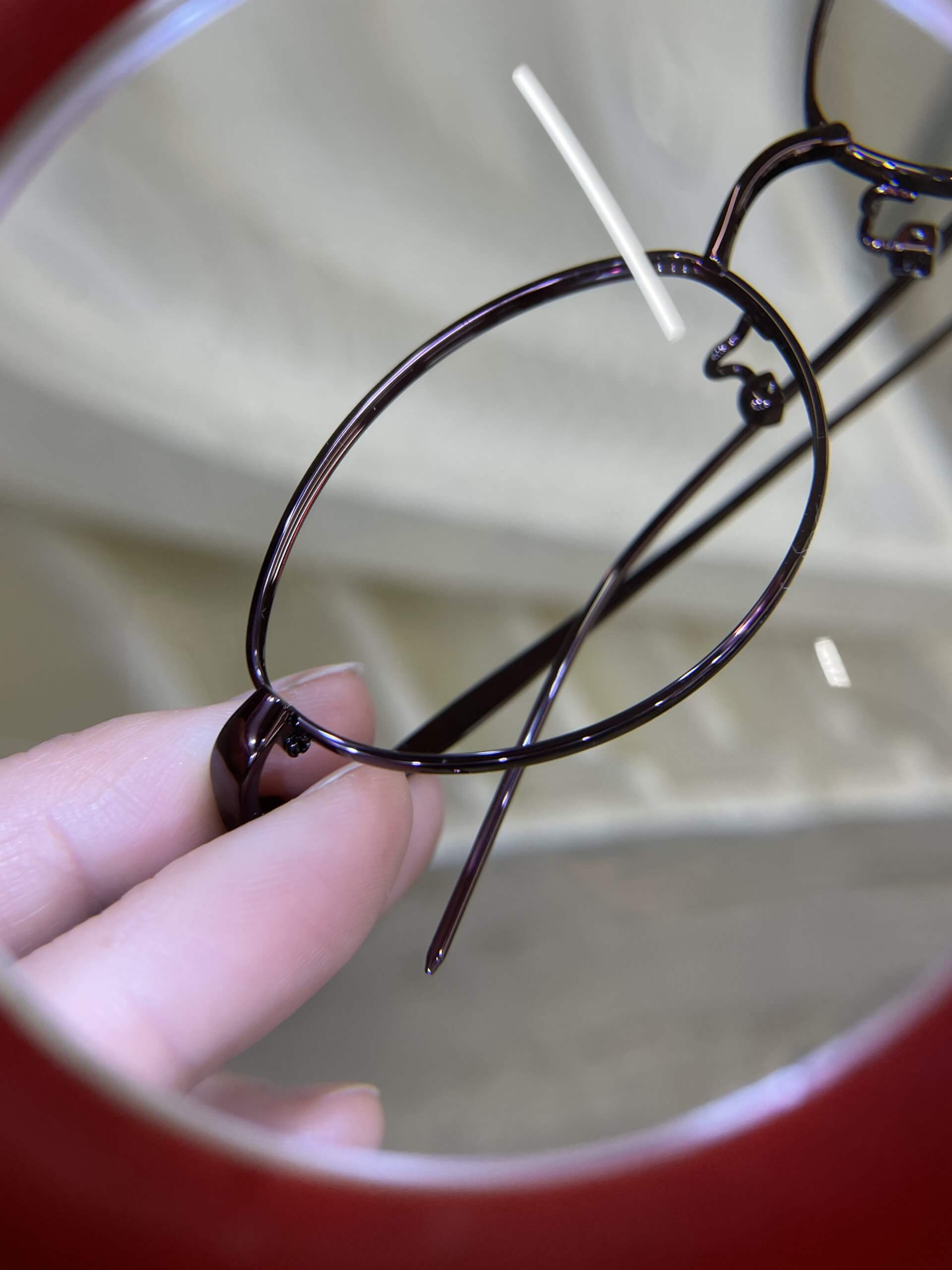 眼鏡市場工場　ルーペでメガネフレームに傷がないか検品している様子