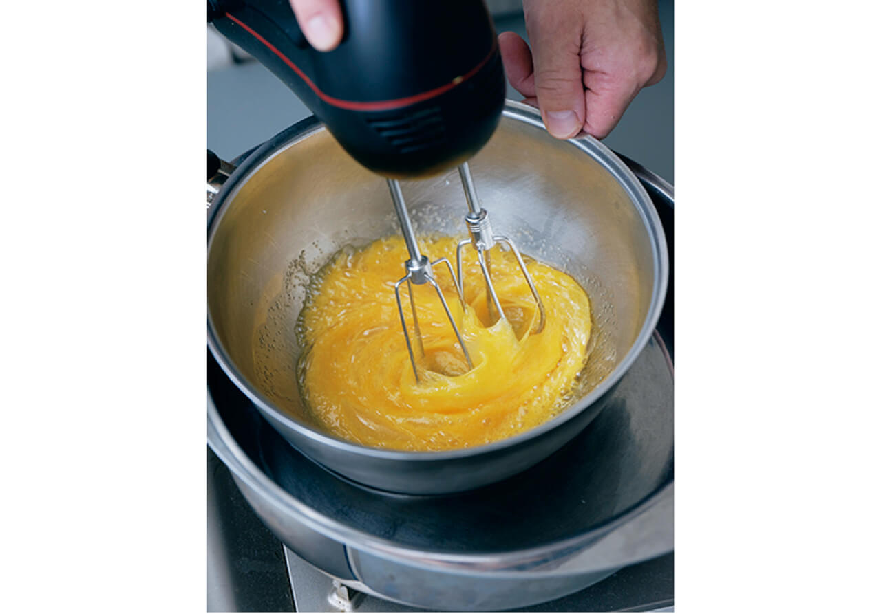 ボウルに卵と砂糖を入れ、ハンドミキサーの低速モードで混ぜ合わせる。湯煎にかけ、人肌（40℃）程度に温まるまで混ぜる