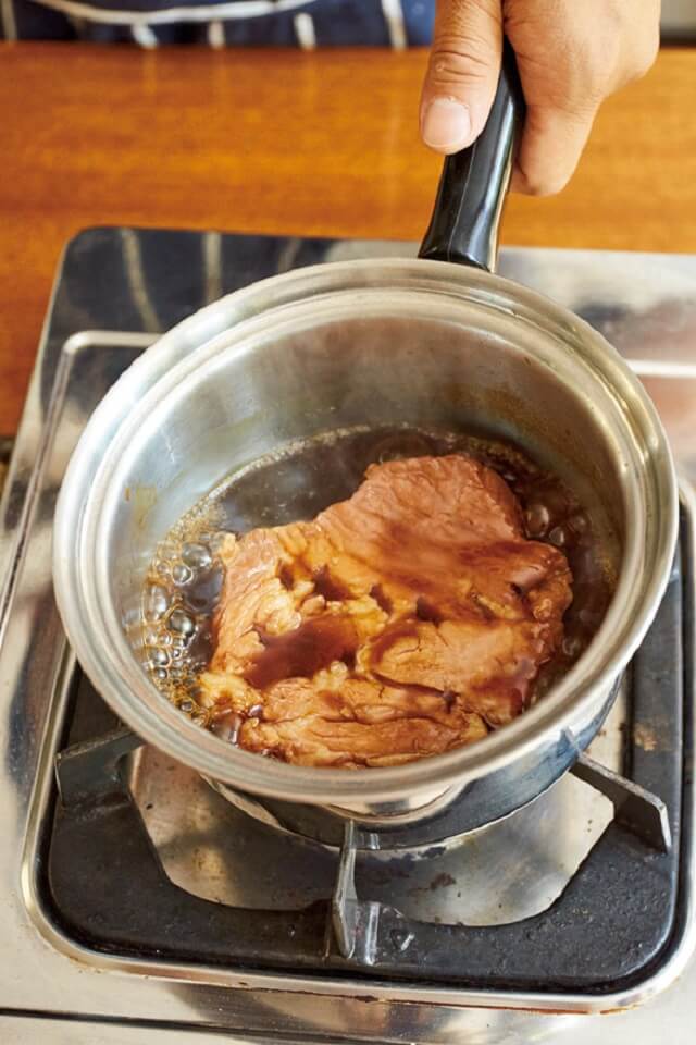 写真：トンカツ用豚肉を調味料とともに小鍋でさっと煮る様子