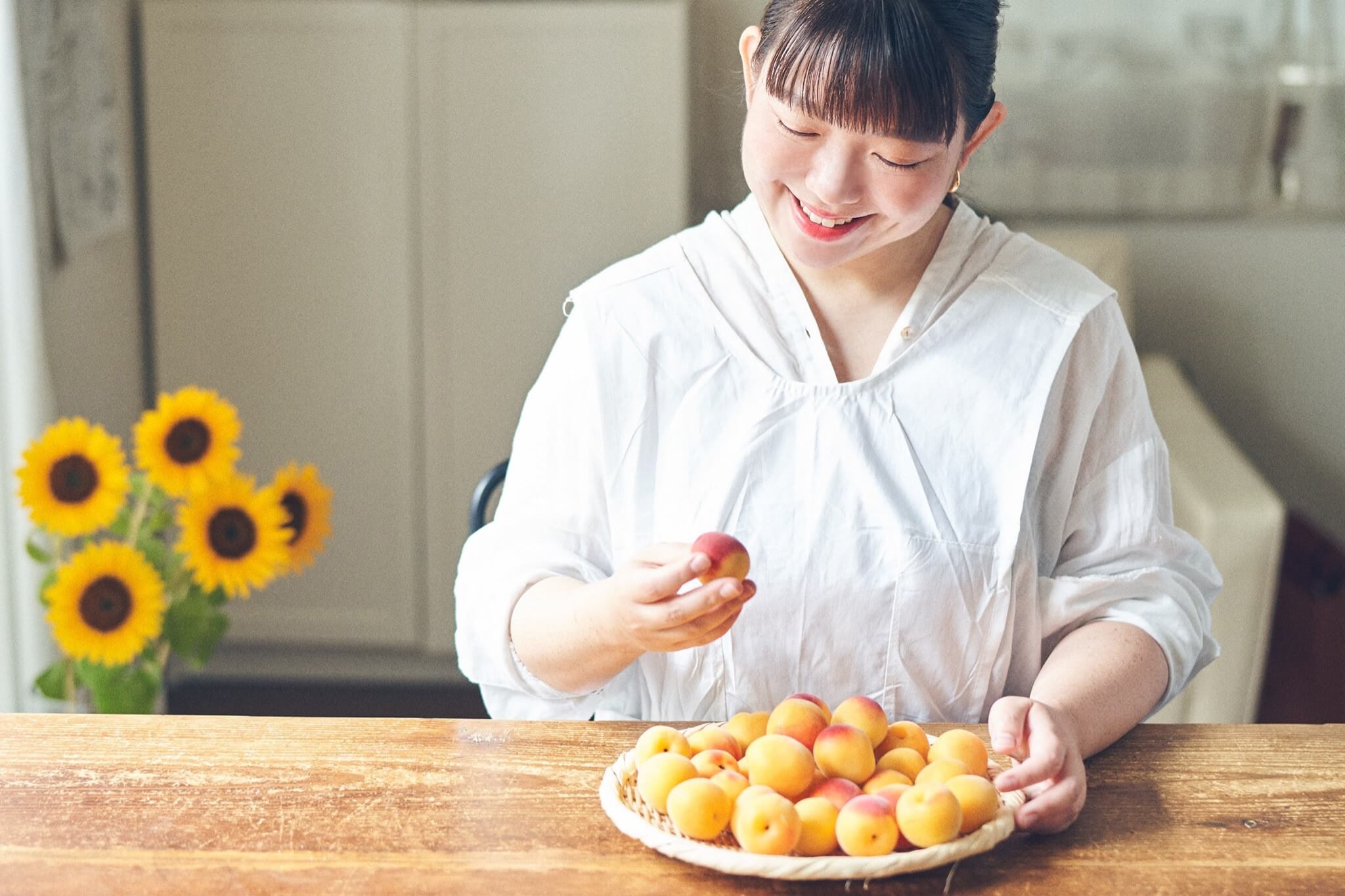 写真：完熟梅を手に取り眺める料理家・今井真実さん