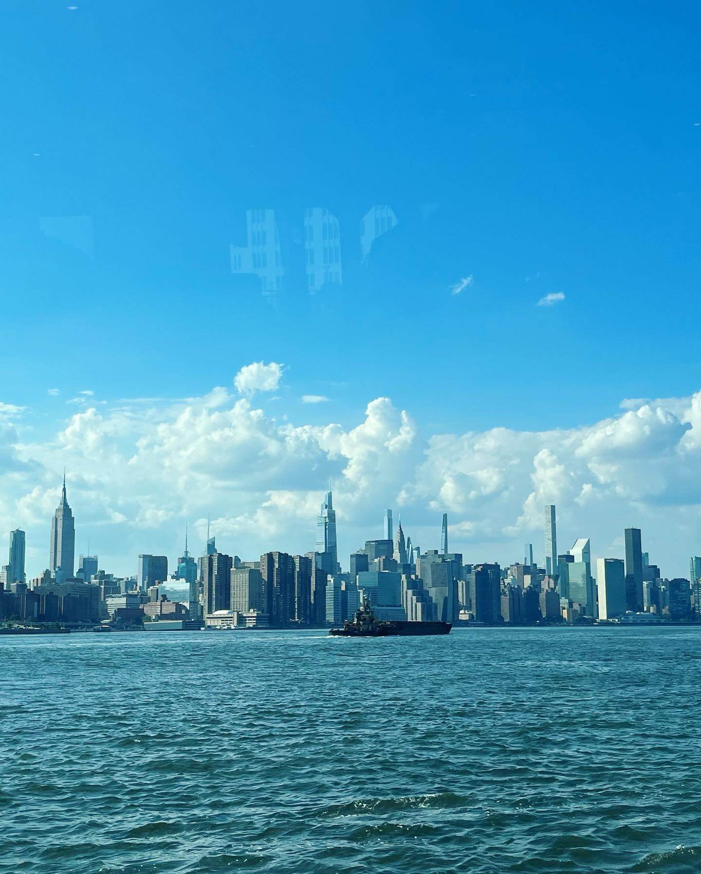 写真：NYの景色。手前に水面。奥にはNYの摩天楼