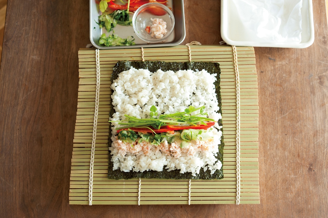 写真：ワタナベマキさんの巻き寿司の巻き方2-2＿ノリにのせたすし飯を広げた上にほかの具材ものせたところ