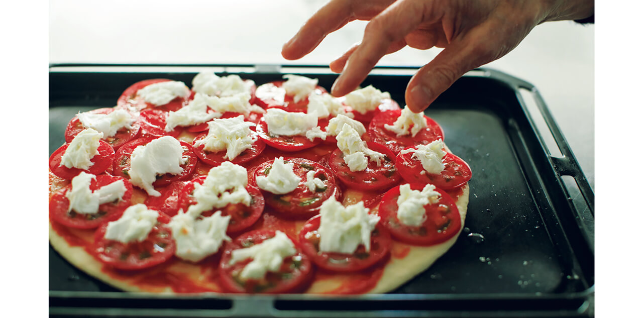 生地にケチャップを塗り、フルーツトマトを重ねずに並べる。トマトの上に手でちぎったモツァレラチーズをのせ、バジルを散らし、塩、こしょうを振ってピザ用チーズをのせる。生地の縁にオリーブオイルを回しかける。