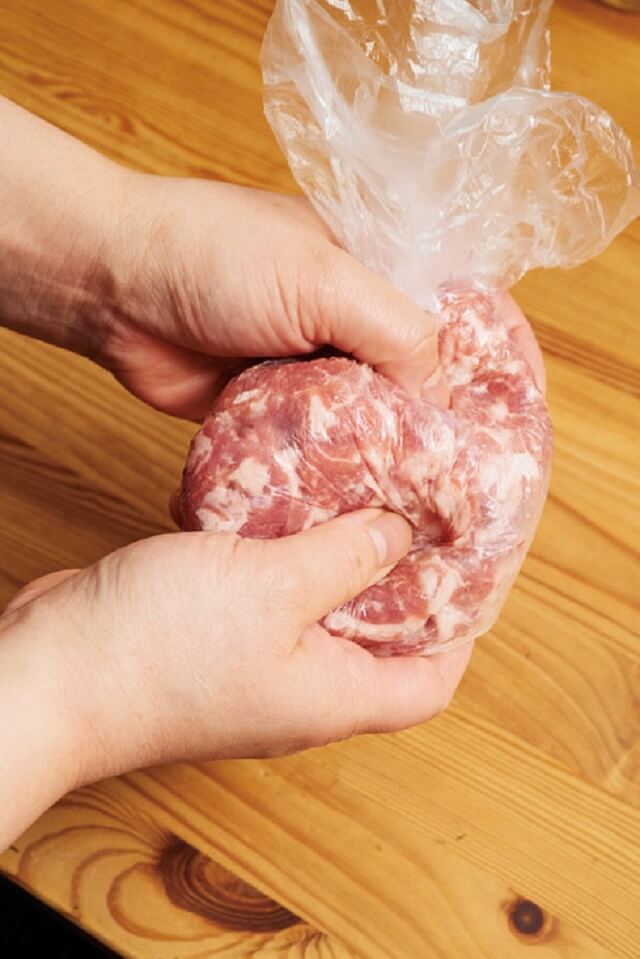 写真：ポリ袋に入れた肉と調味料を、袋の上から両手で包み込むようにしっかり揉む様子