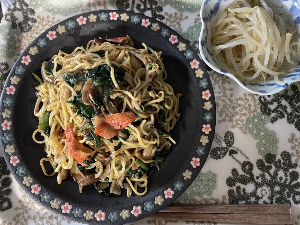 白央篤司さんレシピ「カニかま、青菜、きのこの焼きそば」を40代主婦が作ってみた食卓写真2。三ツ持啓さん作陶のリムに花が描かれたプレートに盛り付けしている。