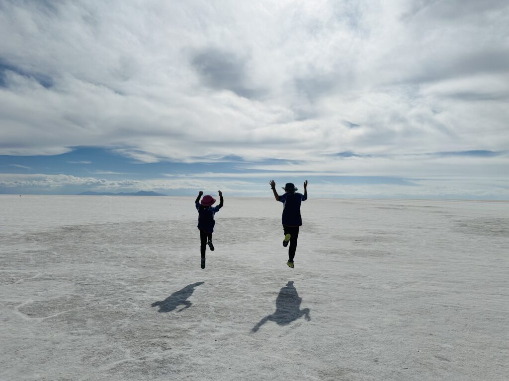 ウユニ塩湖の塩の大地で飛び跳ねる子どもたち