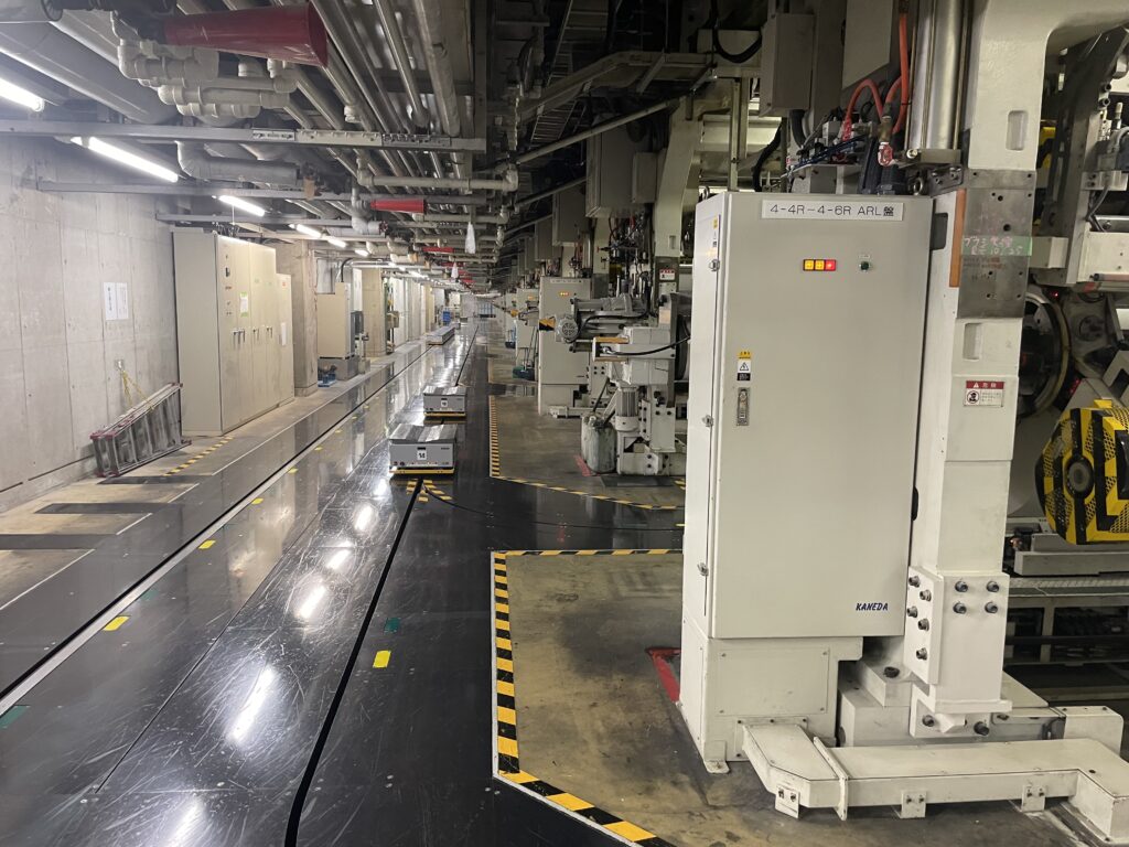 読売プリントメディア横浜工場内、巻取紙の搬送台車がレール上を動く様子。