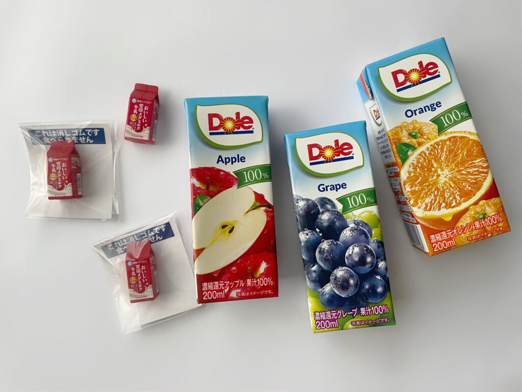 雪印メグミルク野田工場の見学ツアーのお土産は、Dole®ジュースと消しゴム。りんご、グレープ、オレンジ味が並んでいる。メグミルクの赤いパッケージを模した消しゴムが可愛らしい。