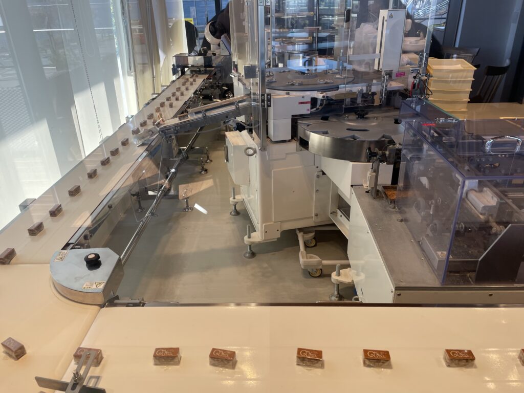 包装済のクルミッ子がベルトコンベアで箱詰めまで運ばれて行く様子