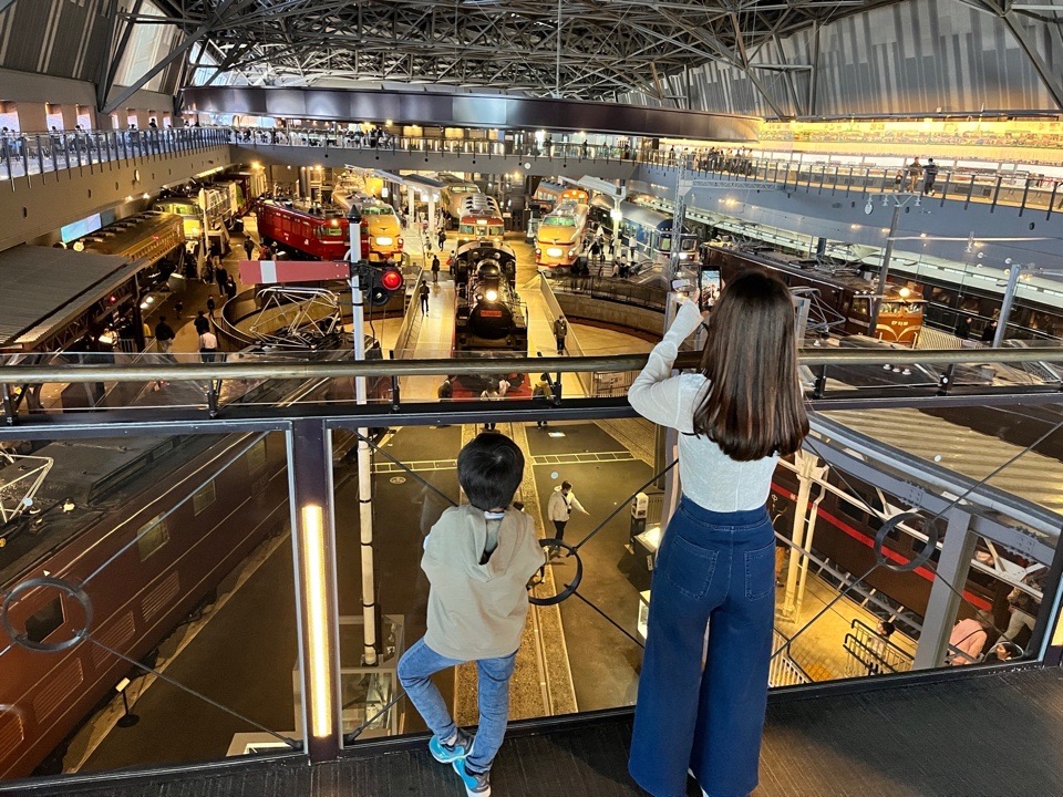 鉄道博物館の二階から一階の写真を撮っている女性と子ども