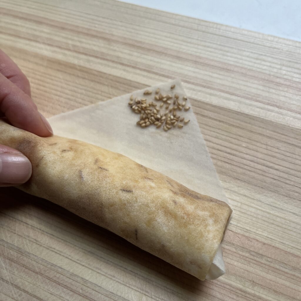 LEE100人隊が春巻きの巻き終わりにゴマやクミンをつけた様子