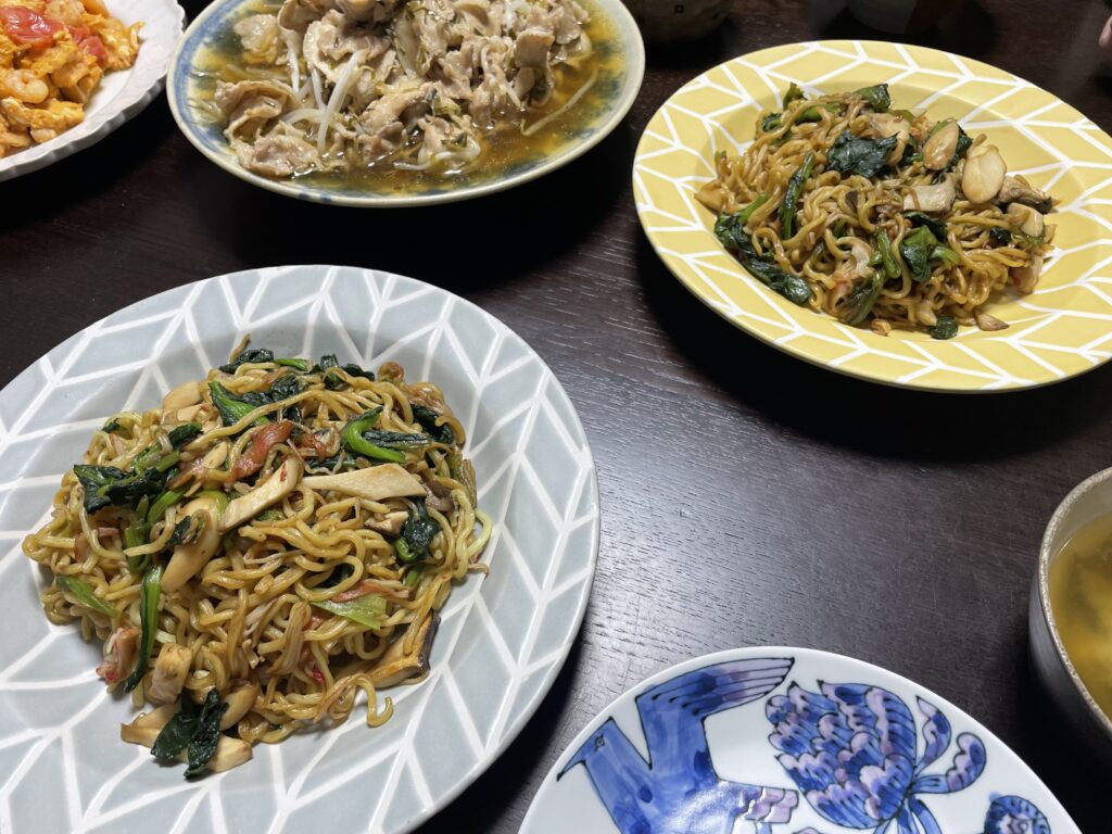 白央篤司さんレシピ「カニかま、青菜、きのこの焼きそば」を40代主婦が作ってみた食卓写真1。黄色やグレーのお皿に盛り付けされている。