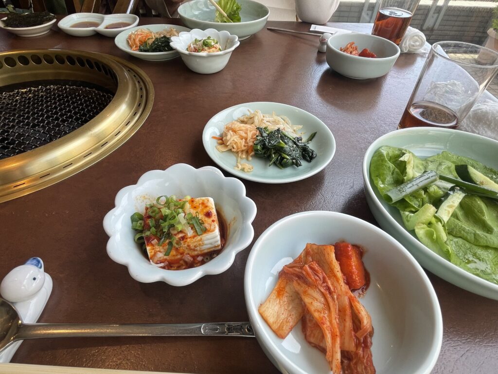 コスパ最高な壱語屋での焼き肉ランチの写真。キムチや豆腐、サンチュサラダやナムルなどが並ぶ。