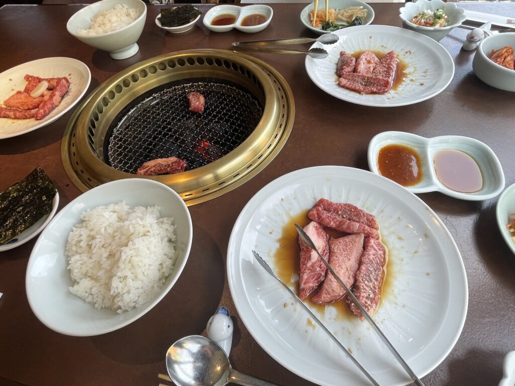 網の上で牛カルビを焼いている様子。タレが2種類用意されている。