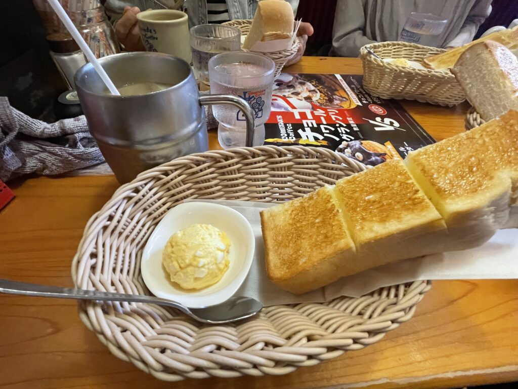 コメダ珈琲店のモーニングサービス。手前はたっぷりサイズのアイスミルクコーヒーに、山食パンにマーガリンが塗ってあり、手作りたまごペーストを付けて。