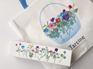 タルティンの花柄ギフトボックスと紙袋の写真。カラフルな花のイラストが目を引く、横浜そごうで購入できる人気の焼き菓子。春の贈り物やおしゃれな手土産として話題のスイーツ。