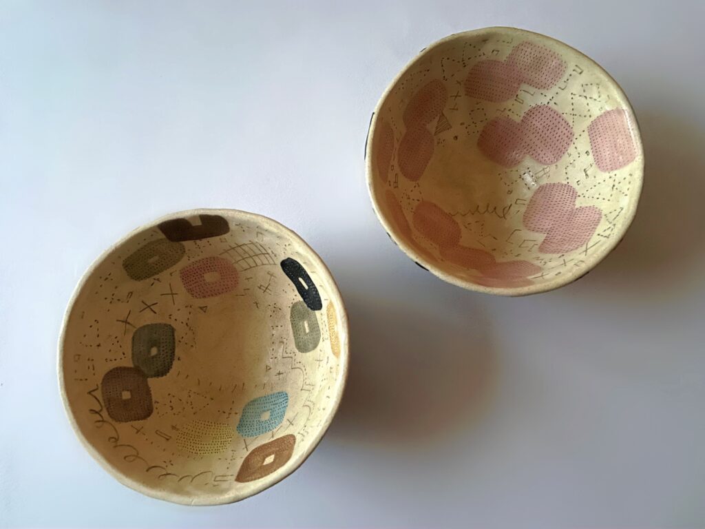 佐藤尚理さん作のボウル2点を内側から撮影。左はカラフルな四角模様、右はピンク色のちょうちょのような模様が散りばめられている。
