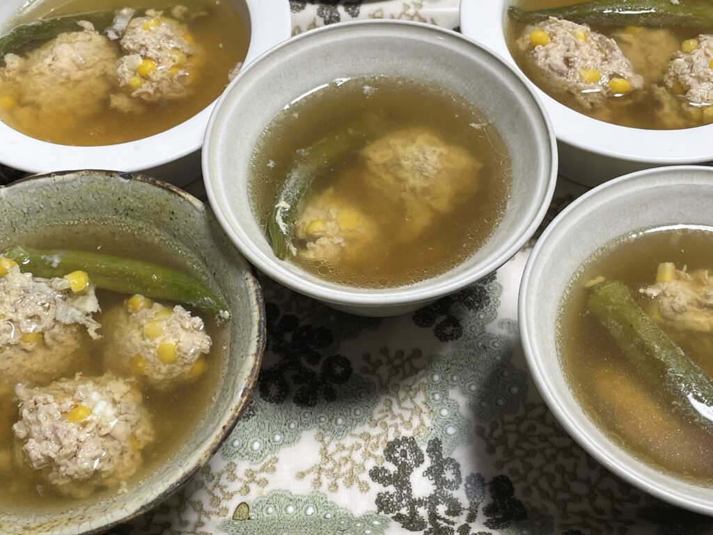 LEE100人隊TBはなが作った、コウケンテツさんのレシピによる、トウモロコシ入りの鶏だんごとオクラが入った和風スープが並ぶ食卓の様子。