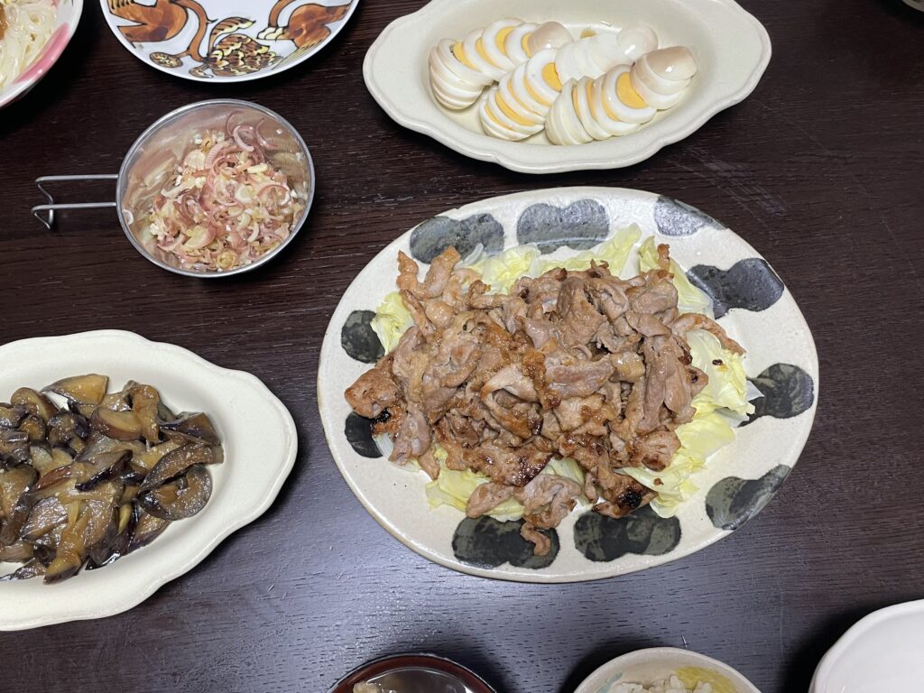 LEE100人隊TBはなが作った、コウケンテツさんのレシピによる豚バラと甘酢みょうがのみそしょうが焼きを石岡信之さん作陶のオーバル皿に盛り付けた。茹で卵のめんつゆ漬け、なすのしょうが炒め、みょうがの甘酢漬けなどが並ぶ食卓。