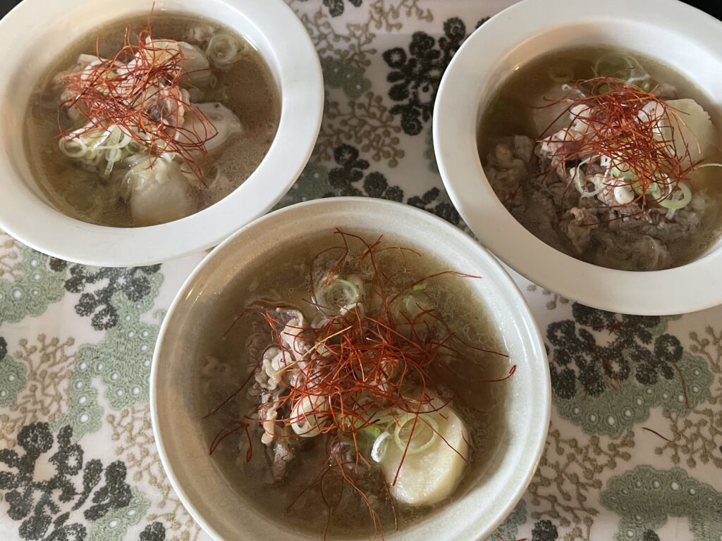 LEE100人隊TBはなが作った、コウケンテツさんのレシピによる牛肉と里芋のスープ。白髪ねぎと糸唐辛子を添えて器に盛りつけた食卓の風景。