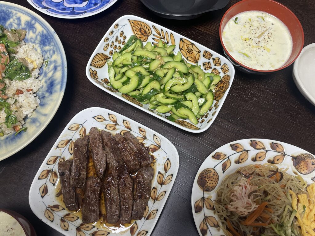 斜めから撮った、LEE100人隊TBはなが作った、コウケンテツさんのレシピによる、きゅうりナムルや牛肉ソテー、ビビンバ風ごはん、春雨サラダ、クリームスープが並ぶ夕食の食卓。