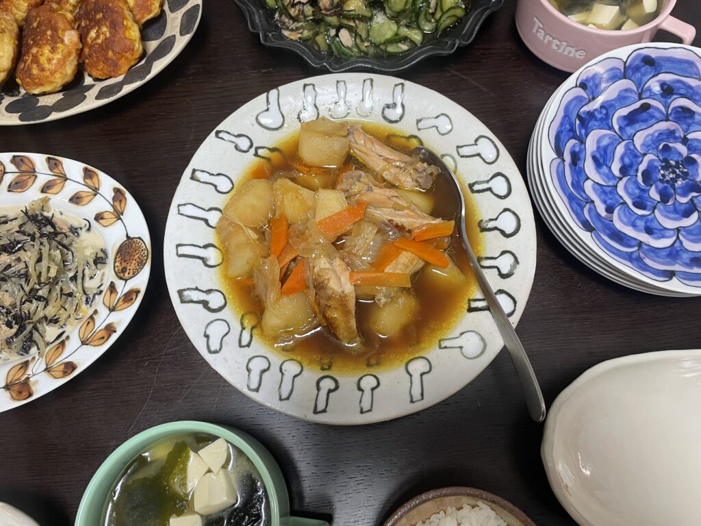 LEE100人隊TBはなが作った、コウケンテツさんのレシピ「手羽中鶏じゃが」。楠田純子さんの吹き寄せシリーズのボウルに盛りつけ、他のおかずや汁物とともに並べた夕食の食卓風景。