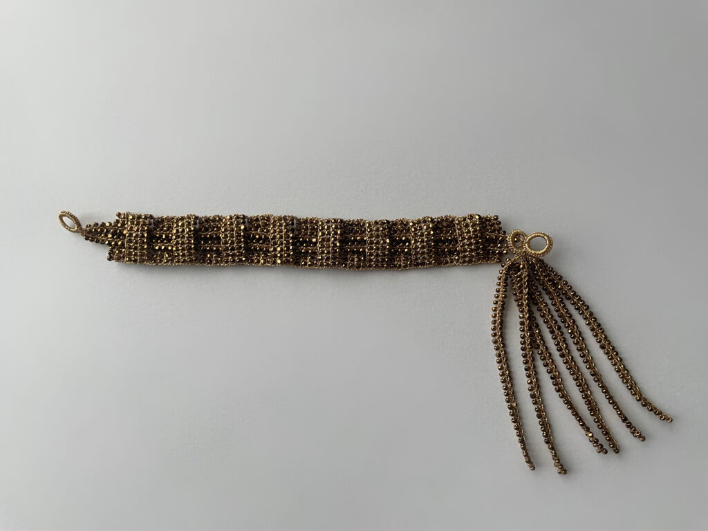 FUA accessoryのtruthシリーズのブレスレット。プリーツ状のパーツに房飾りが組み合わされたデザインで、繊細で華やかな印象。