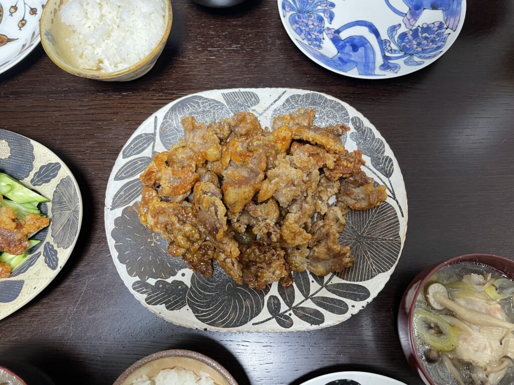 長谷川あかりさんのレシピ「豚こま肉のカリカリ甘味噌絡め」を40代主婦が作ってみた時の写真。鹿児島睦さん作陶の草花模様の図案の器に盛っている。右下には中華スープが注がれた汁椀が写っている。