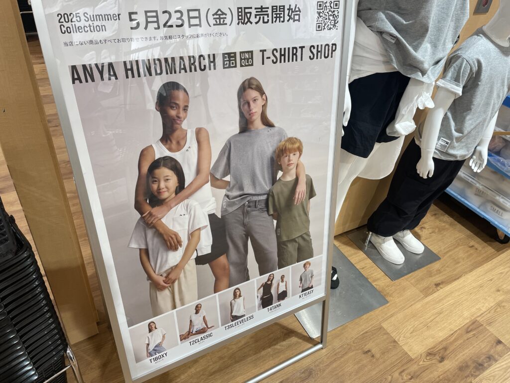 ユニクロ×アニヤ・ハインドマーチの広告写真。5月23日(金)販売開始と書いてあり、TシャツやノースリーブTシャツを着た女性2人と男女の子どもが写っている。写真の隣のマネキンには今回新発売のTシャツを着たマネキンがディスプレイされている。