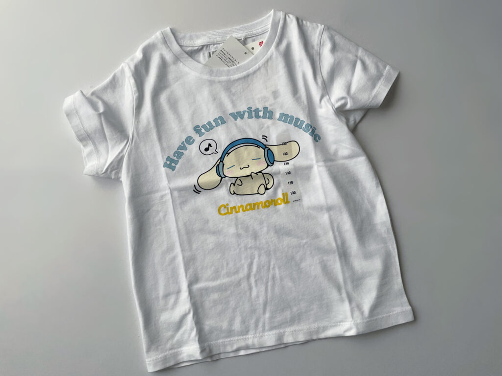 ユニクロ×シナモロール、サンリオキャラクターズのコラボのTシャツ。シナモロールが目を瞑ってヘッドホンで音楽を聴いているデザイン。白地。“Have fun with music”の水色の文字が書いてある。