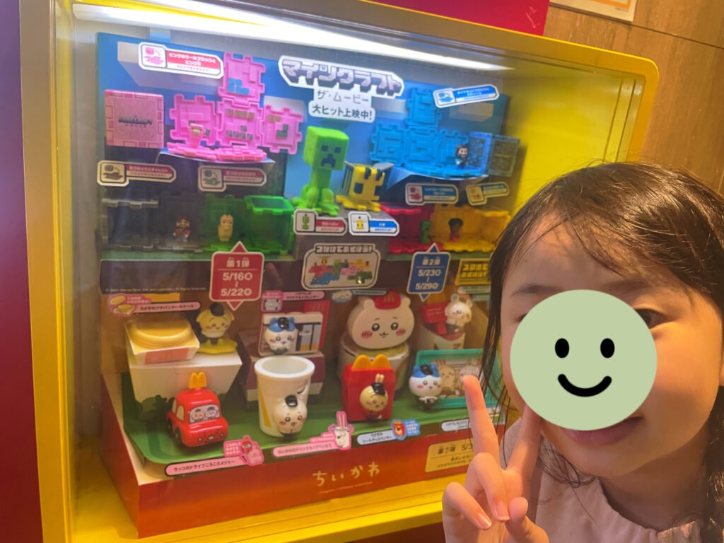 マクドナルド×ちいかわコラボやマインクラフトコラボのグッズが並んでいる。女の子の顔はスタンプで隠してある。