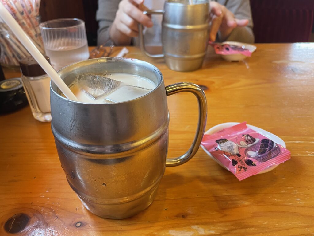 コメダ珈琲店のアイスミルクコーヒー（たっぷりサイズ）と豆菓子の写真。