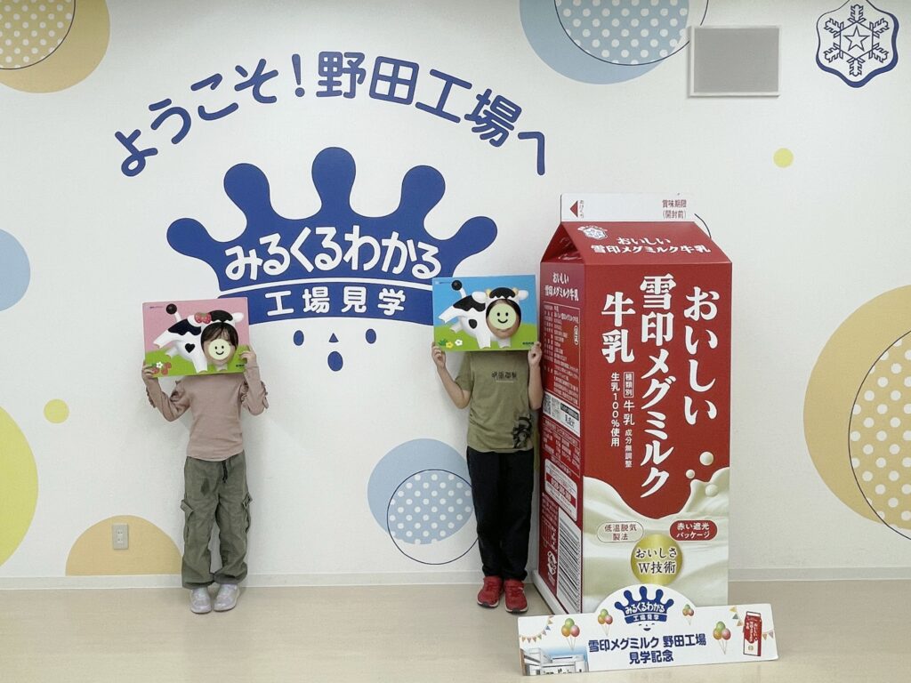 雪印メグミルク野田工場のフォトスポット2。顔はめパネルを持って撮影される小学生男女。