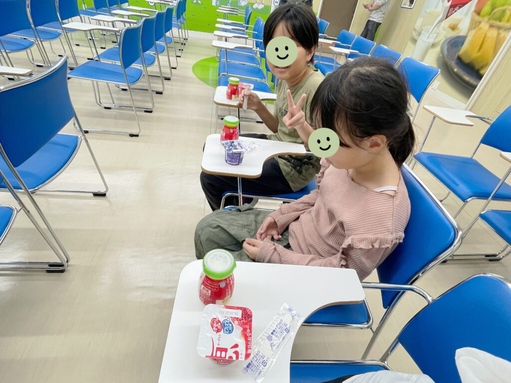 雪印メグミルク野田工場での「みるくるわかる工場見学」ツアー参加中、牛乳とヨーグルトを試食中の小学生男女