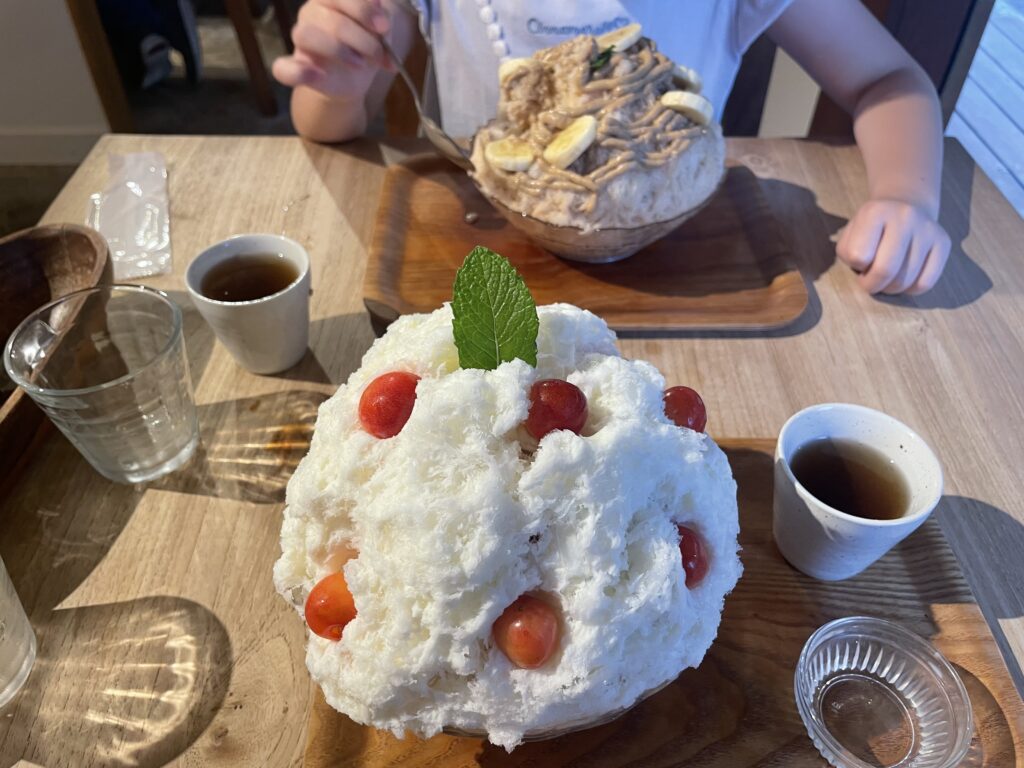 カフェクノップゥのかき氷。手前はさくらんぼミルクのかき氷。奥はバナナアールグレーのかき氷。子どもの上半身が映っている。