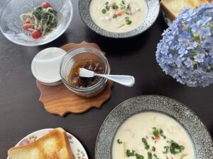 梅ジャムを添えた食卓。トーストやチャウダー、紫陽花の花が並び、ガラス瓶に入った自家製梅ジャムが中央に置かれている。
