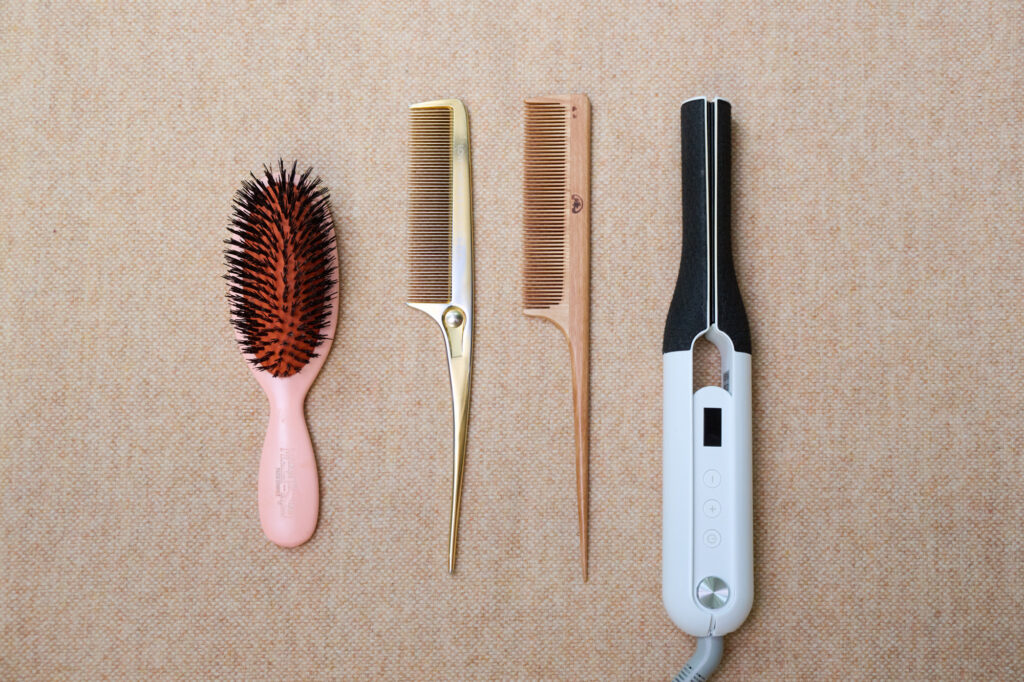 ヘア＆メイクアップアーティストYUTA.  さん愛用ヘアケア道具（左）「長年使い続けたブラシはただの道具ではなく、髪とともに成長する相棒」というYUTA.さんの愛用ブラシ。イギリスのブランド「メイソンピアソン」の子ども用のもの。（中）“黄金色”の2本の櫛。使い込むほどにツヤが出るツゲの櫛と、静電気を抑え、キューティクルがまっすぐ整う「ラブクローム」の純金加工の櫛。（右）立ち上がりが早いCADOのヘアアイロン。スイッチを入れた瞬間一気に180℃まで温度が上がるのでストレスなく使える。